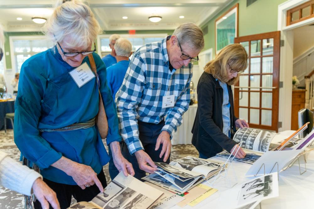 Three alumni looking at past pictures.